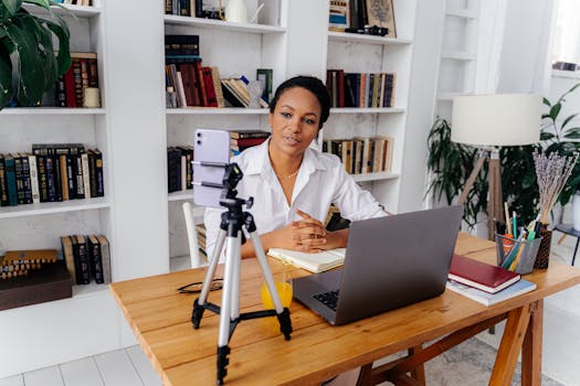 pexels-photo-6266982-6266982 A woman working remotely using a laptop and smartphone in a home office setup with bookshelves.